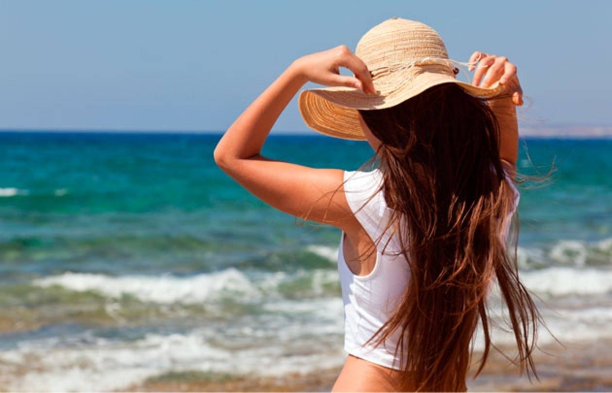 Девушка в шляпе на пляже со спины