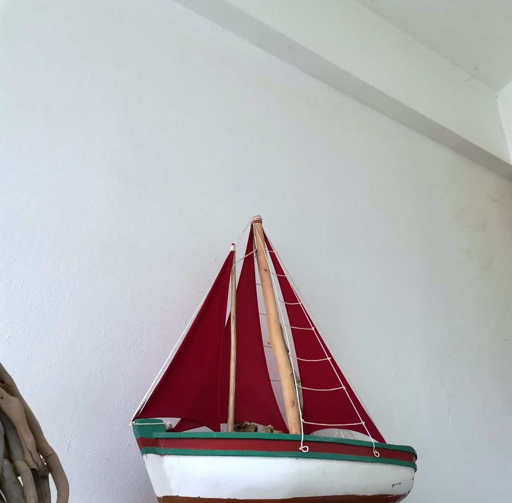 Ένα ξύλινο χειροποίητο καράβι με κόκκινα πανιά